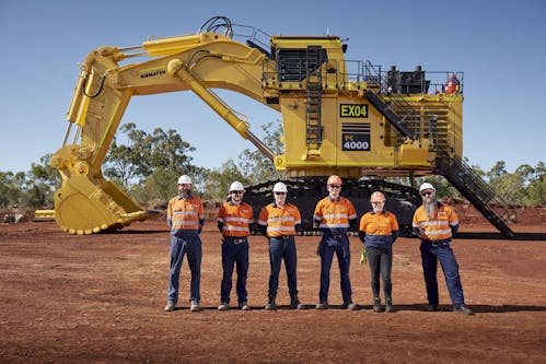 Group of workers standing in front of Komatsu mining machine
